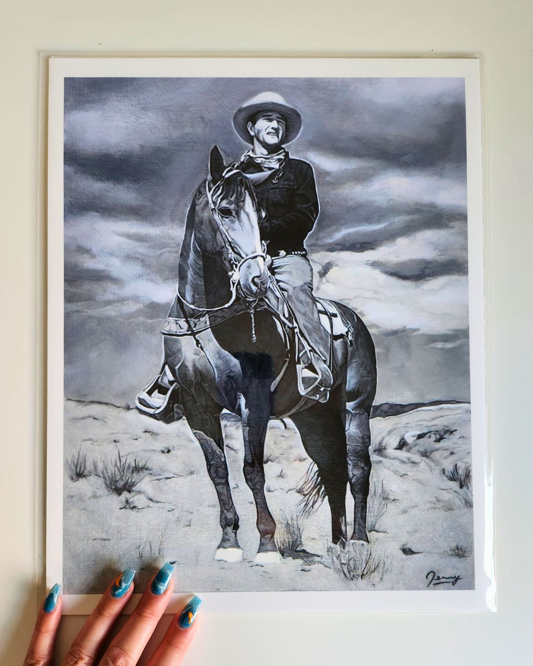 Black and white oil painting print of cowboy on horseback, photographed at an angle in soft natural light